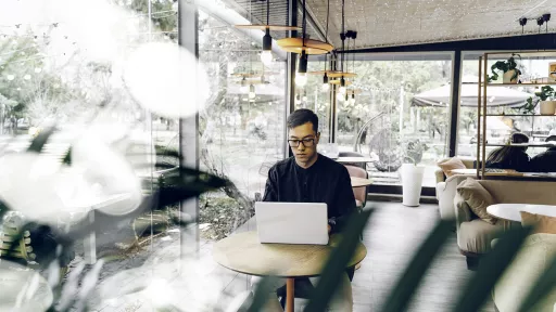 Smart looking young man sitting with a laptop in a cafe.